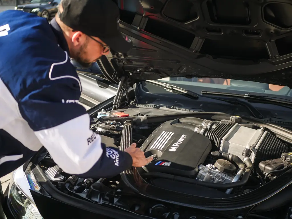 Christopher Lacavé penché sur le compartiment moteur d’une BMW